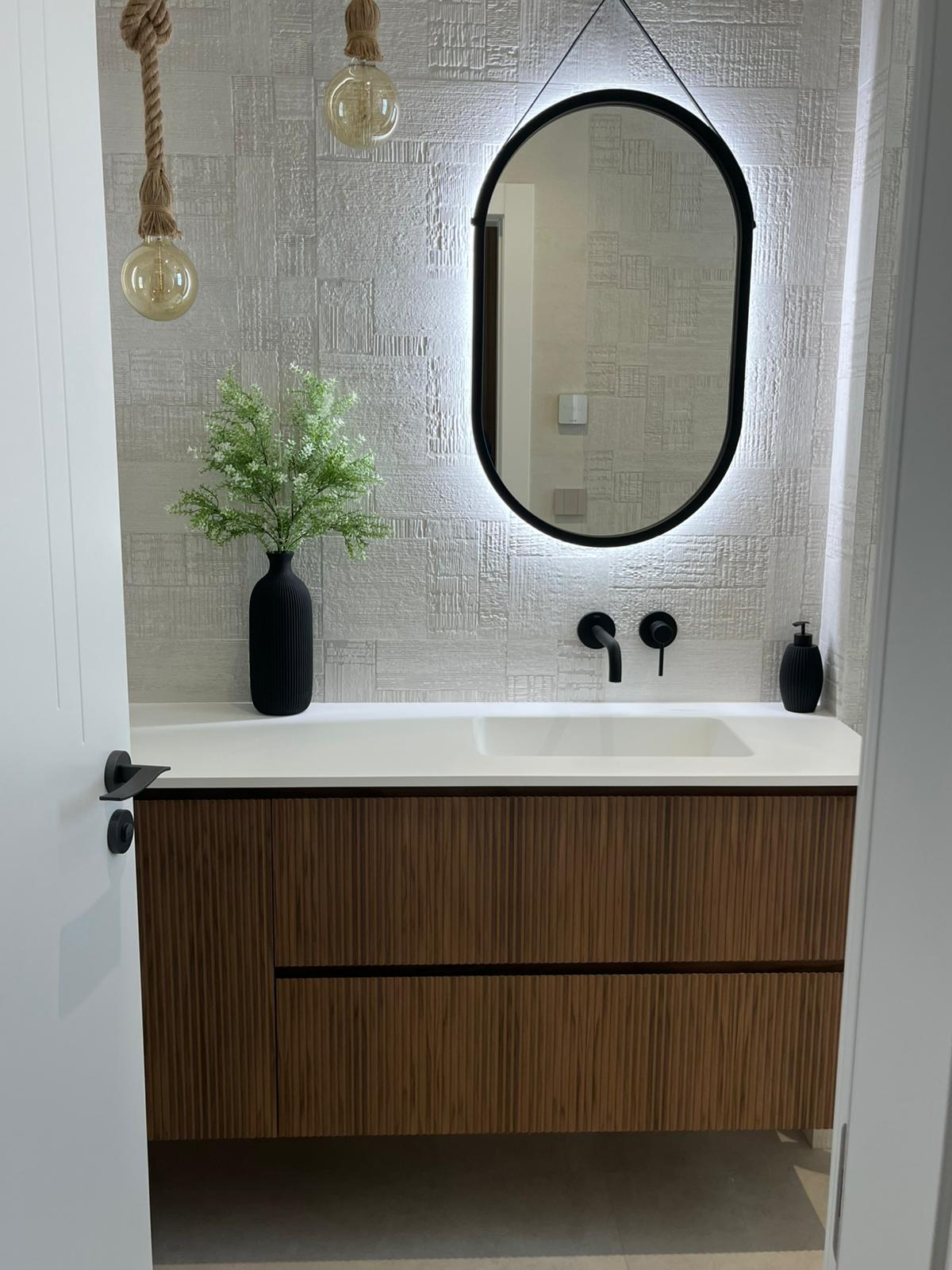Baño con azulejos texturizados y espejo ovalado